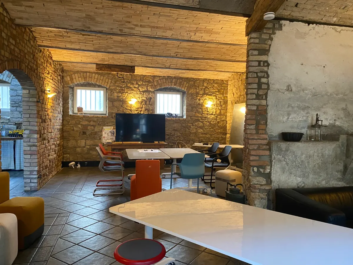 Arbeitsraum im Erdgeschoss mit Bruchsteinwänden, Fliesenboden und großem Tisch